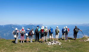 Höhenangst durch ein Coaching oder eine Kurzzeittherapie bei Angstfreier leben überwinden Eine Gruppe von Wanderern mit Rucksäcken steht im Gebirge an einem Hang und schaut ins Tal. Sie sehen entspannt aus.